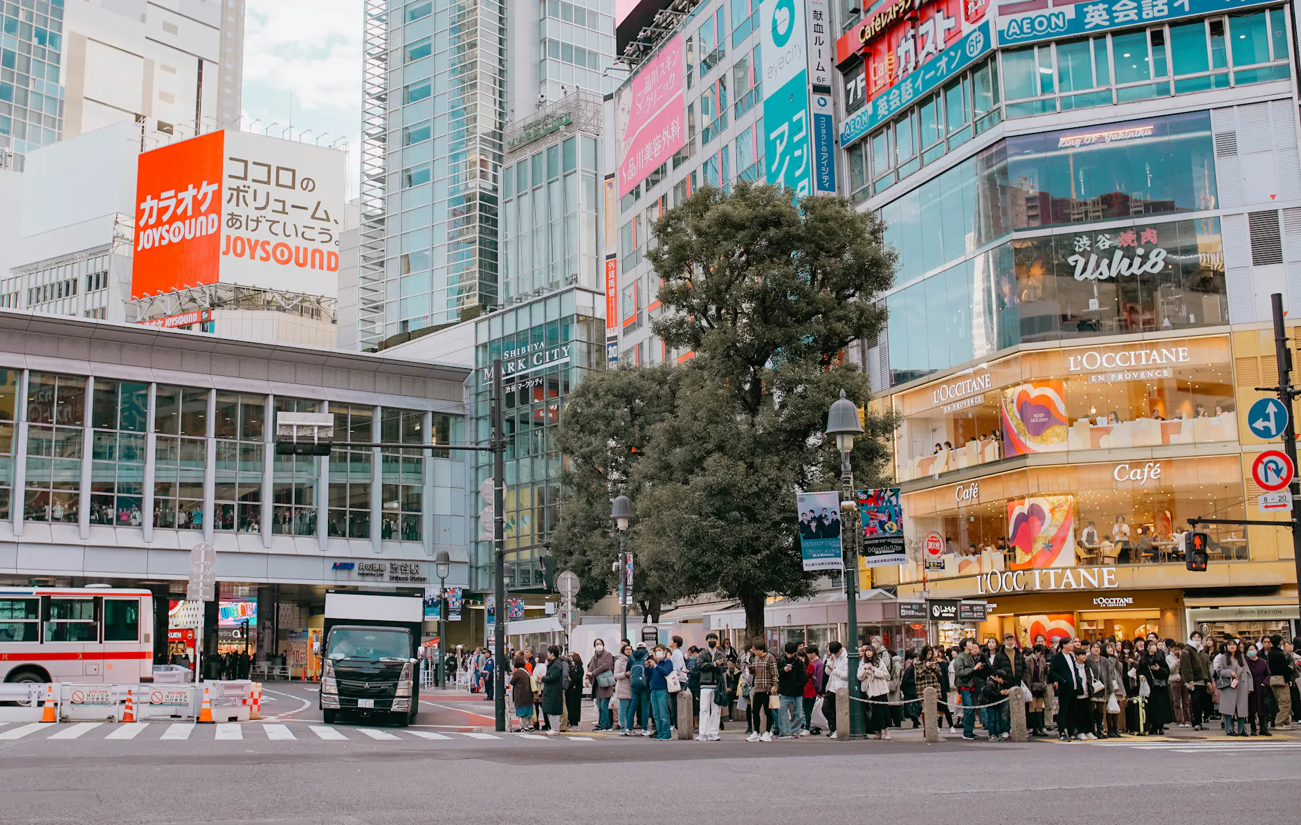 People waiting at the Shibuya crossing in Tokyo, showcasing vibrant urban life and architecture.