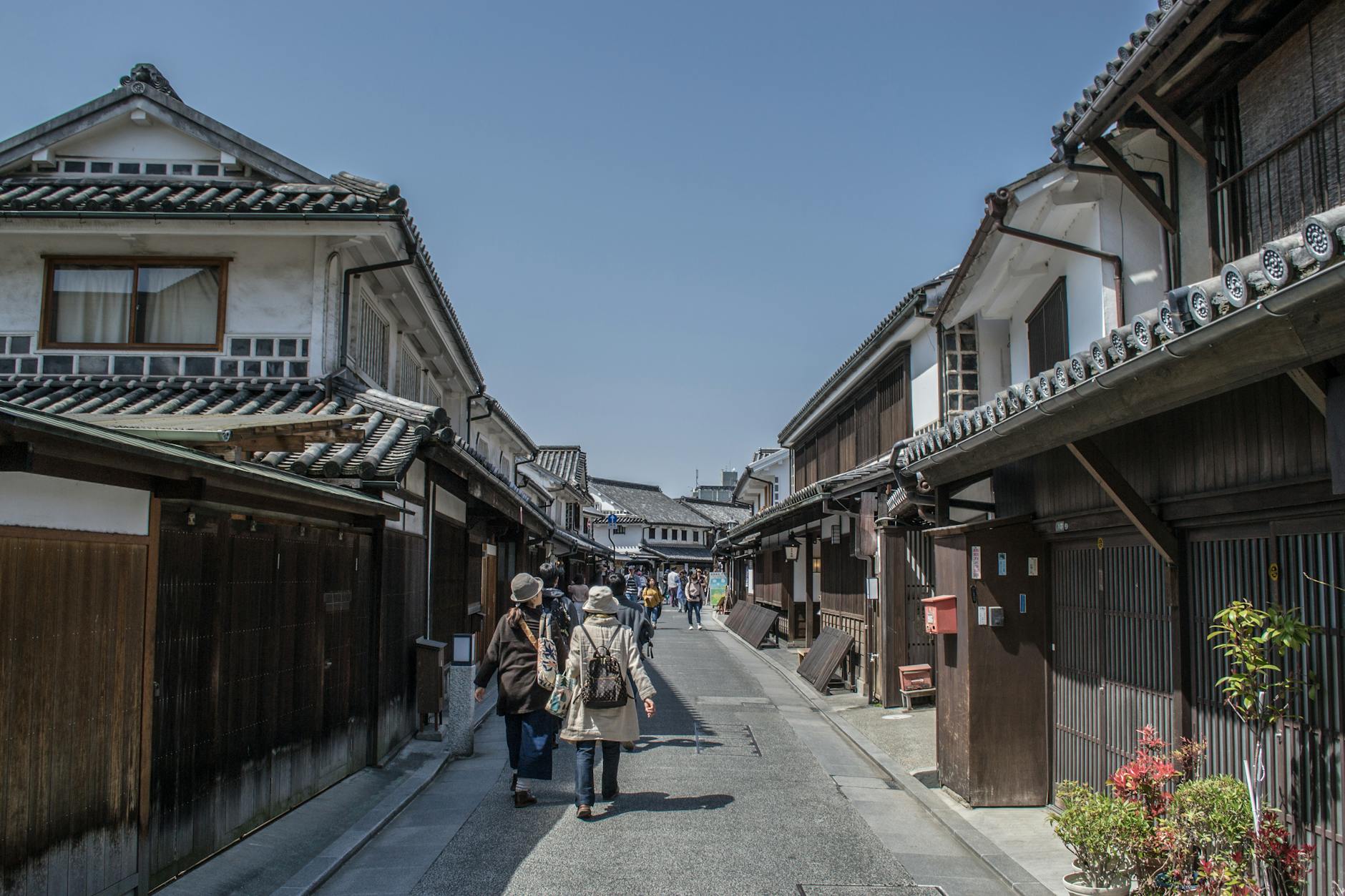 Traditional Japanese street scene in Kurashiki, featuring historic architecture and visitors walking.