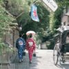 Two women wearing kimonos walk down a traditional street in Kyoto under a parasol, evoking cultural elegance.