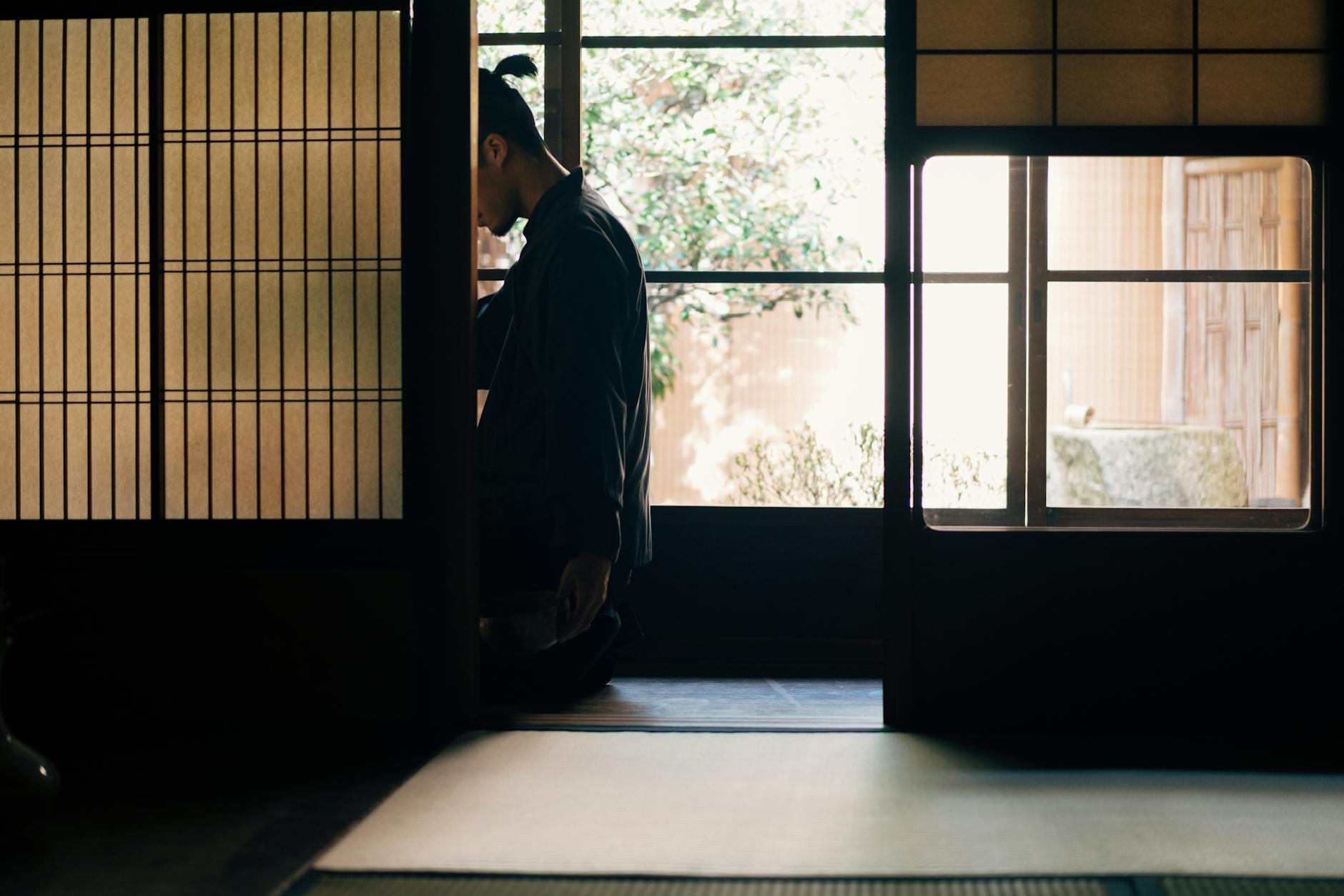 A person meditates in a tranquil Japanese room with soft light filtering through shoji screens.